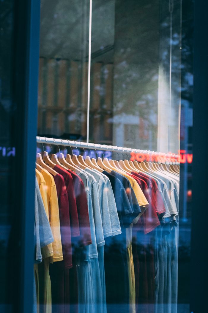 The Art of Drawing Readers In: Your attractive post title goes here Colorful t-shirts hanging in a store window, showcasing a vibrant display.